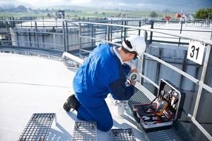 Técnico de serviço instalando um radar de onda guiada na parte superior de um tanque